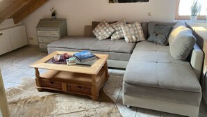 A cozy living room with a sectional sofa, a wooden coffee table, and a painting on the wall. - Alpennest Comfortable Holiday Residence (Fuessen)