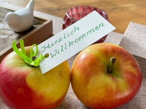 Two apples with a tag that reads "Herzlich Willkommen" placed between them. - Alpennest Comfortable Holiday Residence (Fuessen)