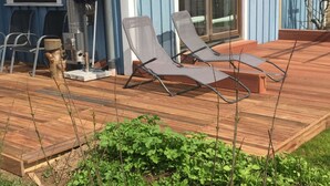 A wooden deck with two lounge chairs, a grill, and a potted plant. - Schwedenhaus am Kai 14i (Grossenbrode)