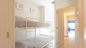 Een slaapkamer met stapelbedden en een deur naar een gang.