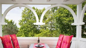 An outdoor patio with a table and two chairs, surrounded by white arches and a view of trees. - Modern Apartment Near Seabeach (Binz)