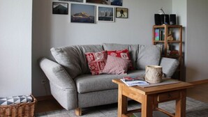 A living room with a grey sofa, a wooden coffee table, and a bookshelf. - Hochgrat View in Steibis, Haus Akelei (Oberstaufen)