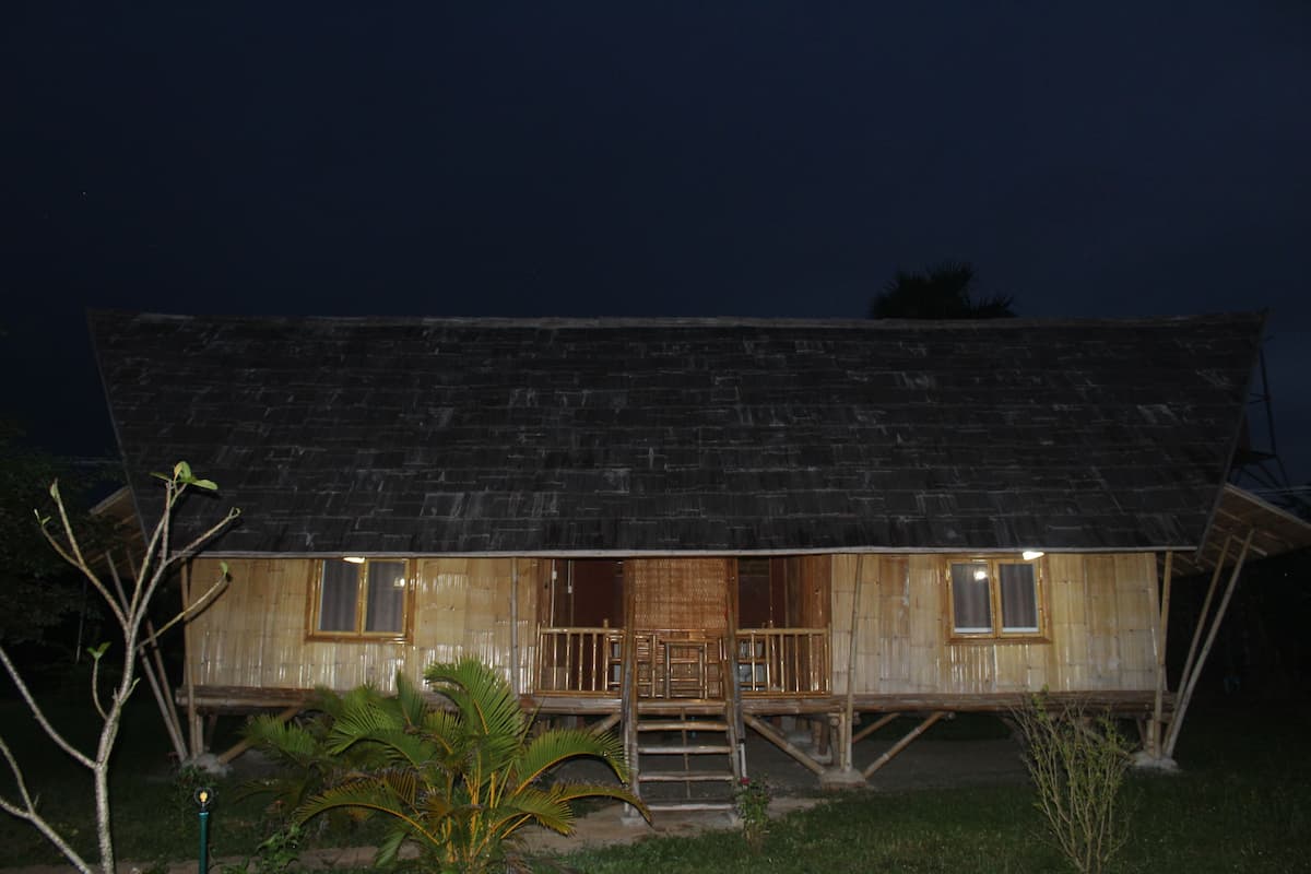 A wooden house with a porch and a staircase leading to the entrance.