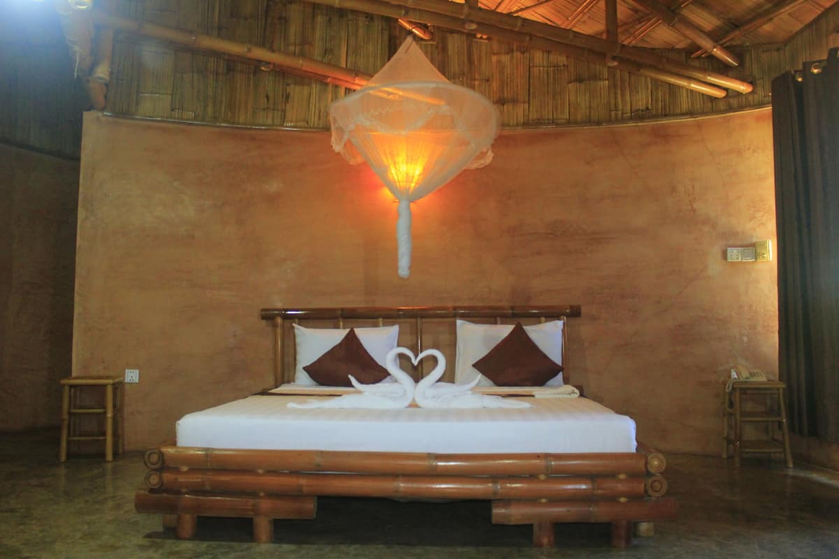 A bed with a wooden headboard, two pillows, and a decorative swan design on the bedspread.