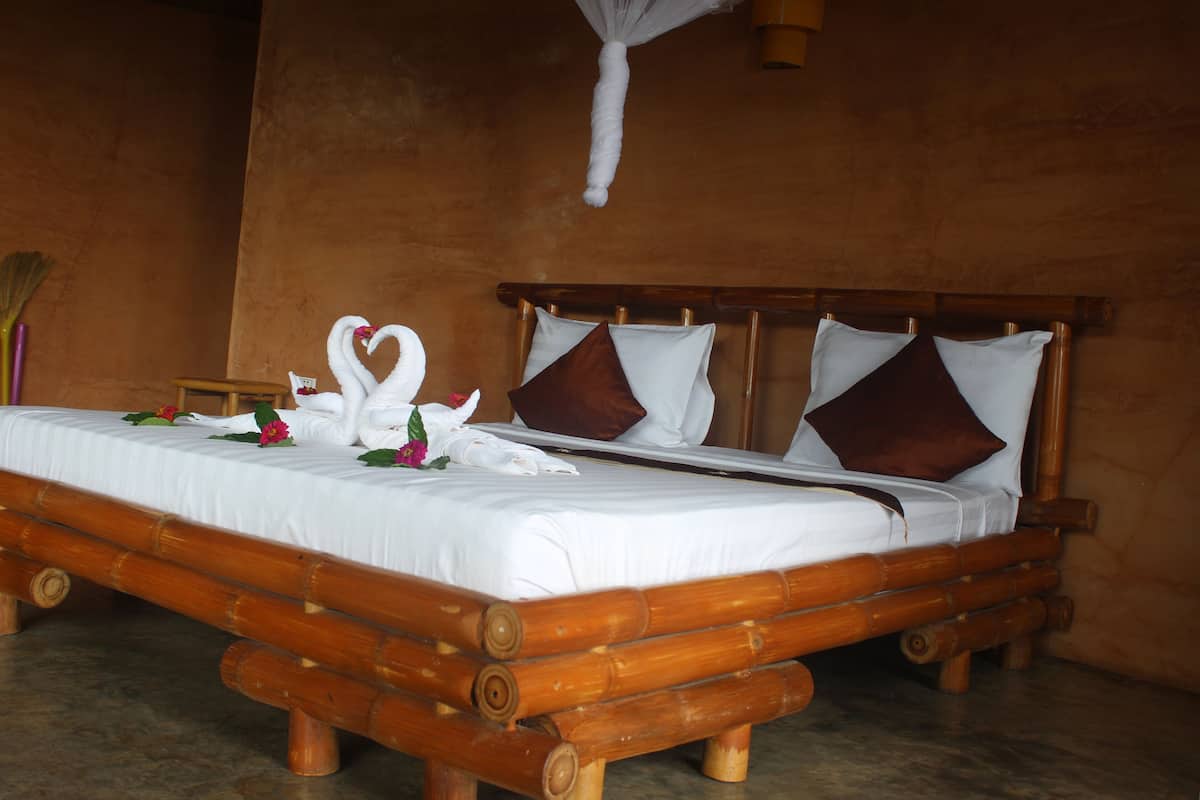 A bed with a wooden frame, white bedding, and decorative swan pillows.