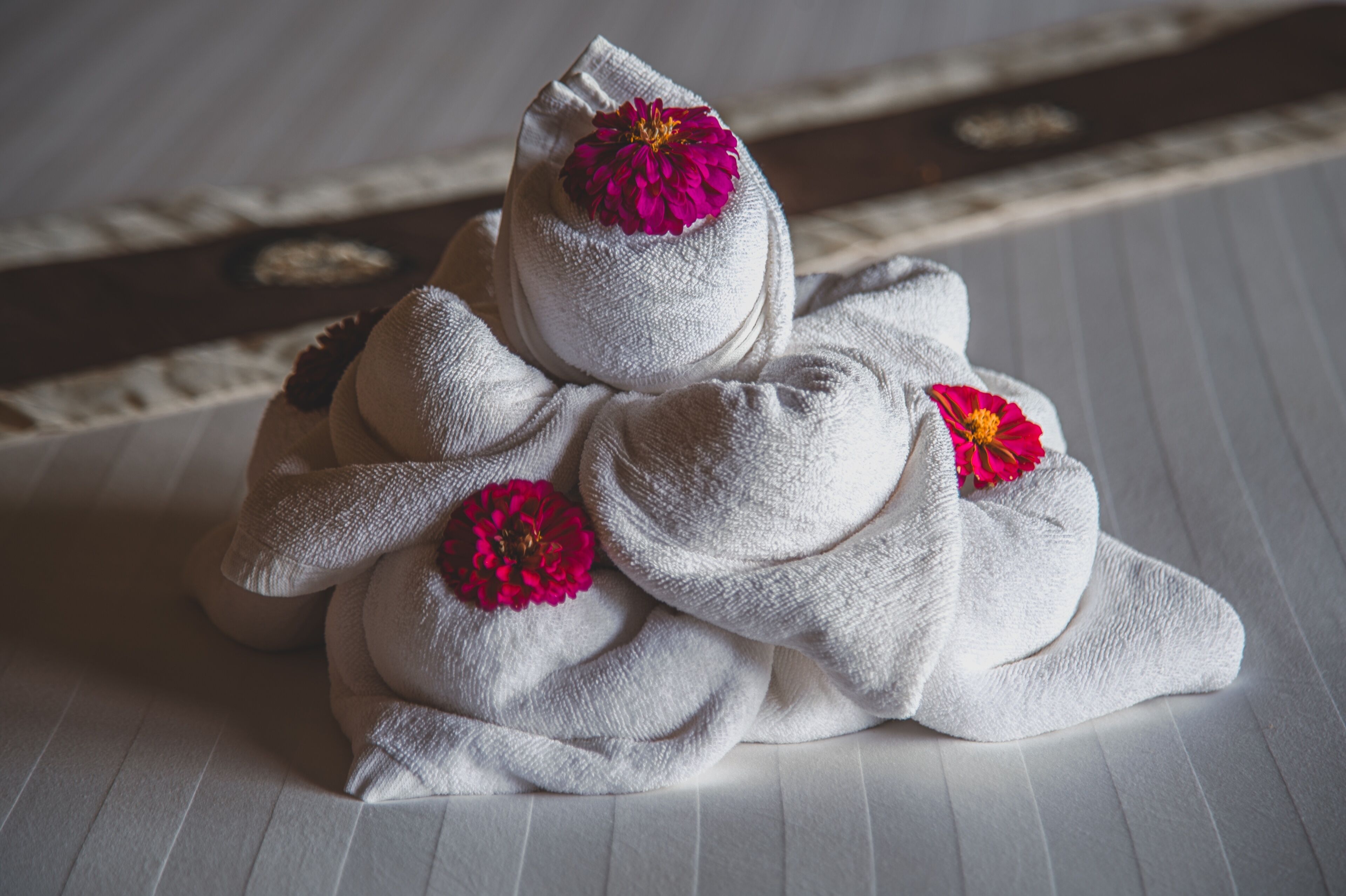 Un ordinato mucchio di asciugamani con fiori decorativi su un letto.