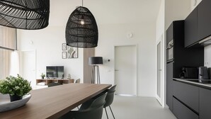 Uma cozinha moderna com armários pretos, uma mesa de jantar de madeira e duas luminárias pendentes.