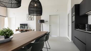 Een moderne keuken met zwarte kastjes, een houten eettafel en twee hanglampen.