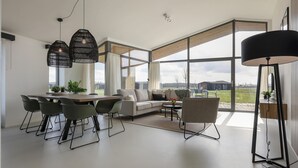 Uma sala de estar moderna com área de jantar, janelas amplas e vista para o exterior.