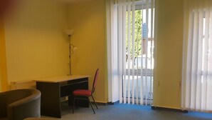 A room with a desk, a chair, a radiator, and a window with blinds.