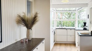 A modern kitchen with white cabinets, a dark countertop, and a window providing a view of greenery outside. - Luxury Seaside Retreat - By Traum Ferienwohnungen (Haderslev)