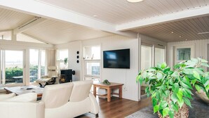 A spacious living room with a white sofa, a wooden coffee table, and a large potted plant. - Luxury Seaside Retreat - By Traum Ferienwohnungen (Haderslev)