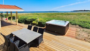 A wooden deck with a hot tub, outdoor seating, and a view of the beach. - Luxury Seaside Retreat - By Traum Ferienwohnungen (Haderslev)