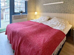 Ein Schlafzimmer mit einem Bett, einem Fenster, einer Heizung und einer Wand mit einem Blattmuster.