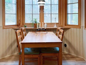 A dining area with a wooden table and chairs, a candle holder, and a window with a view of trees. - 6 Person Holiday Home in Yngsjo (Yngsjo)