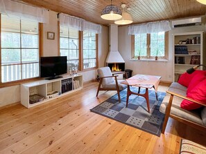 Ein gemütliches Wohnzimmer mit Kamin, Holzböden, Fernseher und Bücherregal.
