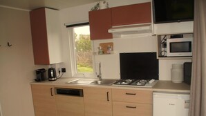 A compact kitchen with a dishwasher, a sink, a stove, a microwave, and a small refrigerator. - Lovely Chalet in Schoonloo With Patio (Schoonloo)