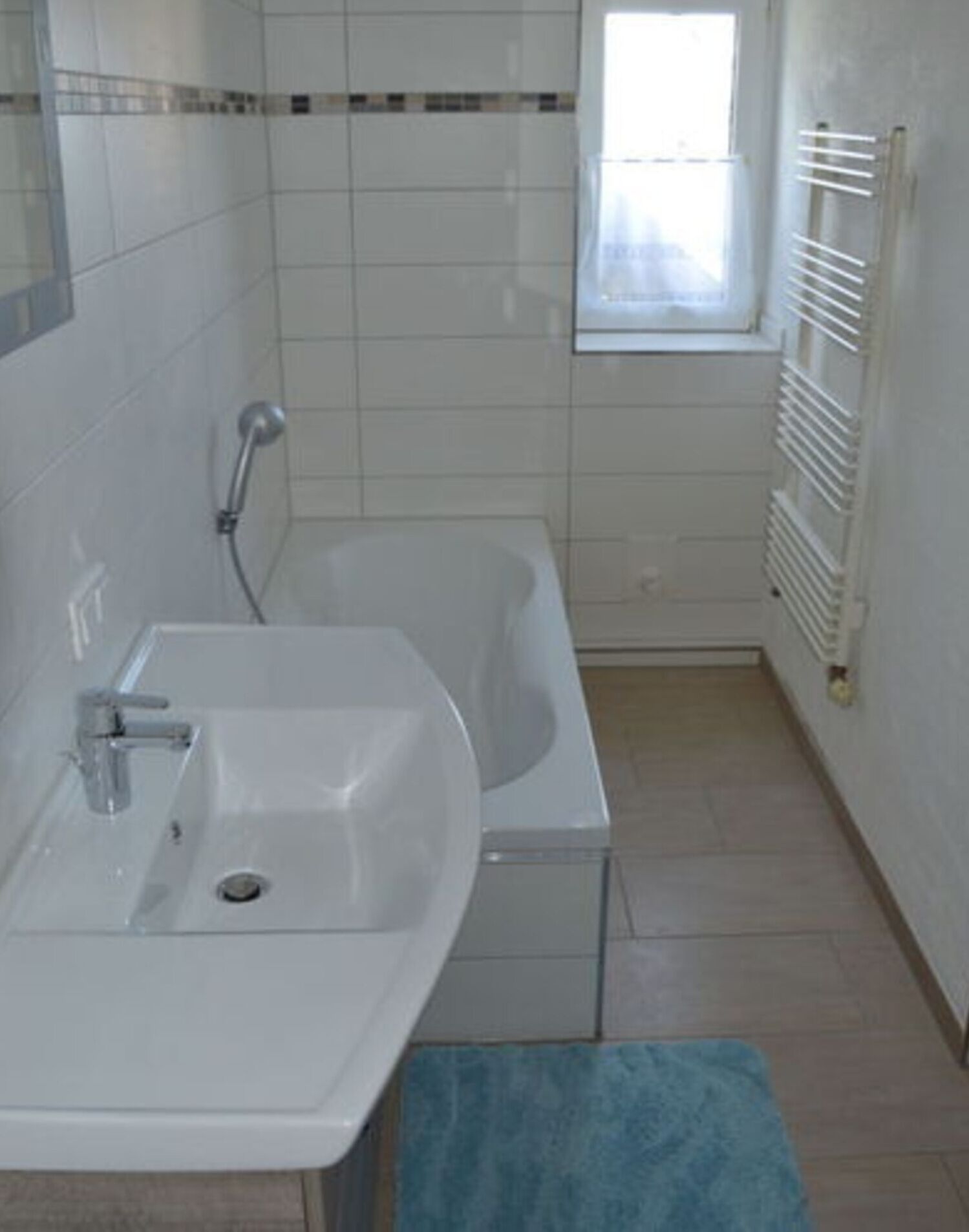 A bathroom with a sink, bathtub, and a window.
