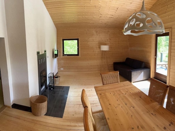 A wooden interior with a dining table, chairs, a sofa, a lamp, and a television. - Inviting Apartment in Schotten (Schotten)