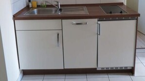 A compact kitchen with a microwave, sink, and dishwasher. - Holiday Apartment Villa in the Park (Wangerooge)
