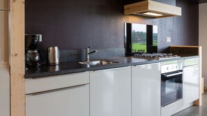 A modern kitchen with a built-in stove, sink, and coffee maker. - Peaceful Farmside Bungalow (Heeten)