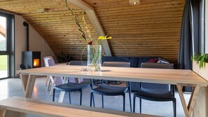 A modern interior with a wooden ceiling, a long dining table, and black chairs. - Peaceful Farmside Bungalow (Heeten)