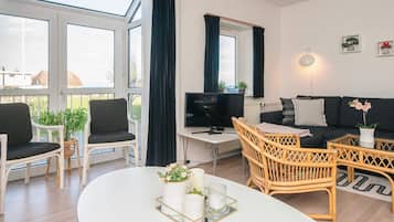 En moderne stue med sofa, stole, et fjernsyn og et spisebord med en bakke.