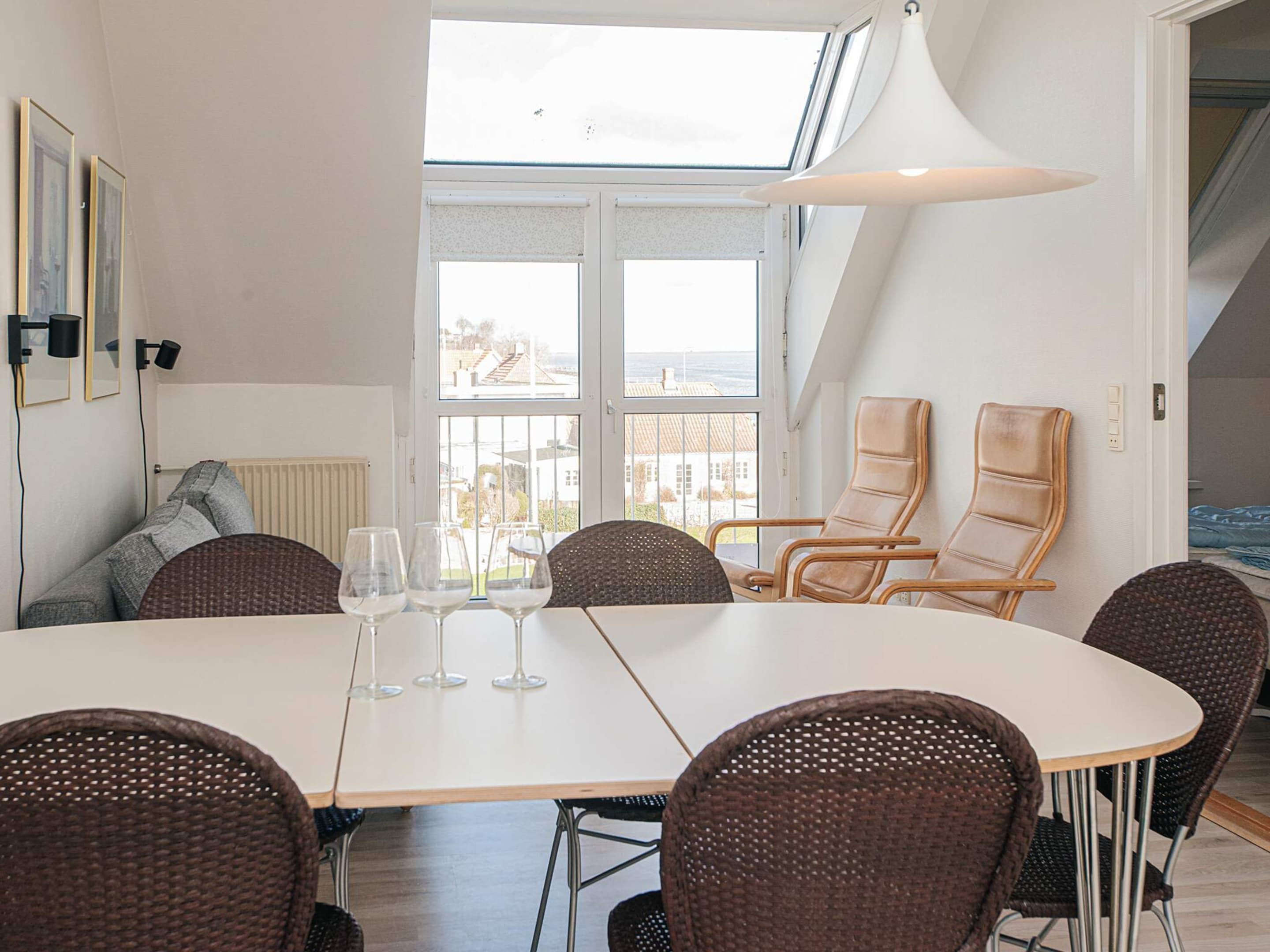 A dining area with a table, chairs, and three wine glasses.