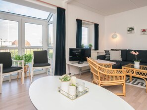 A modern living room with a sofa, chairs, a TV, and a dining table with a tray. - 6 Person Holiday Park Home in Hejls (Hejls)