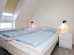 Un dormitorio con dos camas, un tragaluz y lámparas de noche.