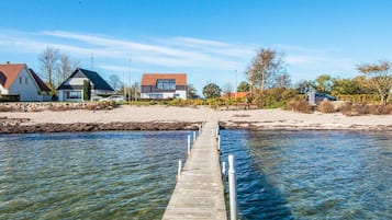 Un muelle de madera que se extiende hacia un cuerpo de agua tranquilo, con casas en la orilla opuesta.
