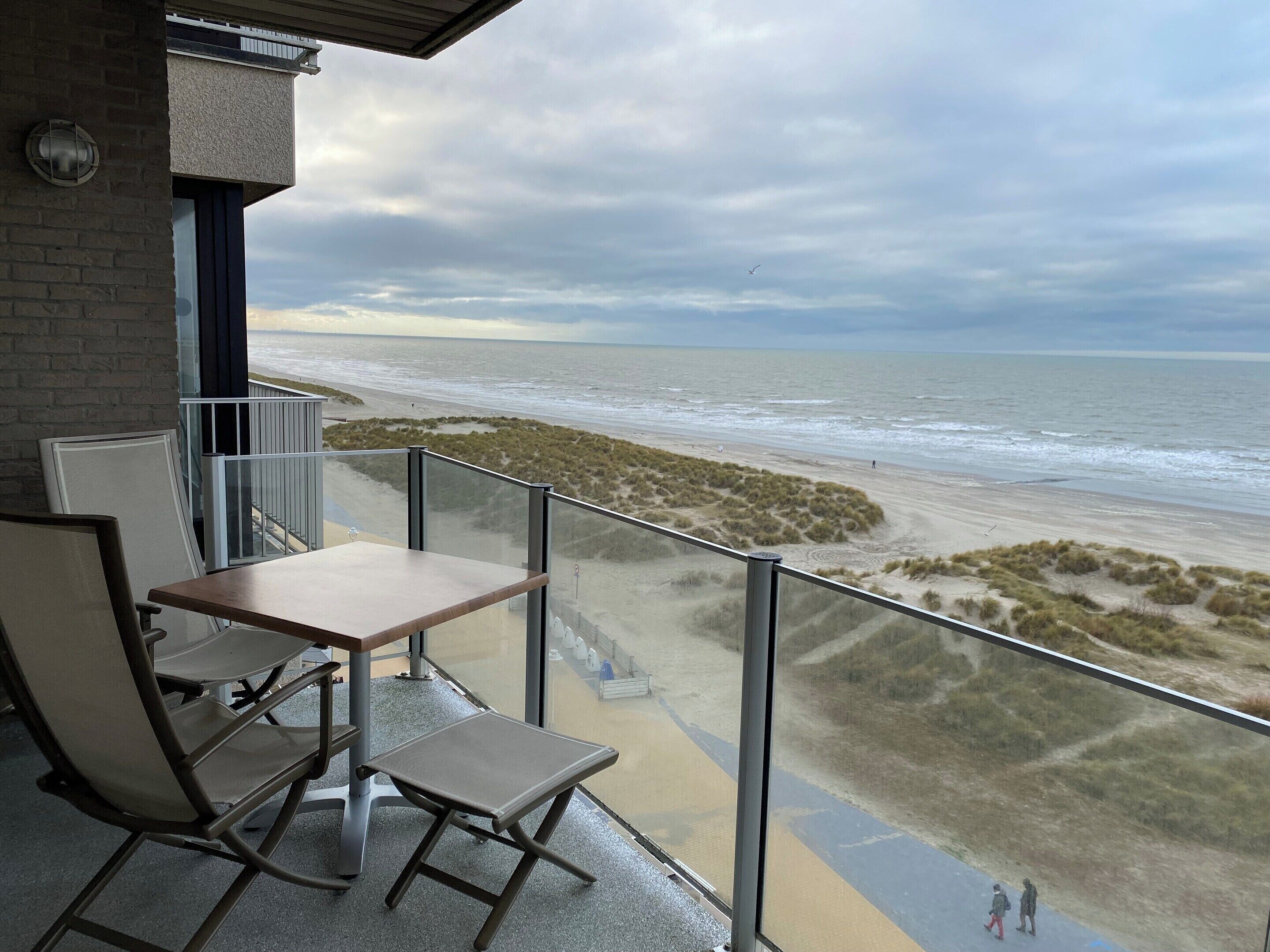 A balcony with a view of the beach and ocean.