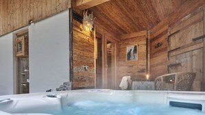 A wooden cabin interior with a hot tub, rustic decor, and a fireplace. - Felsenhutte Modern Retreat (Graen)