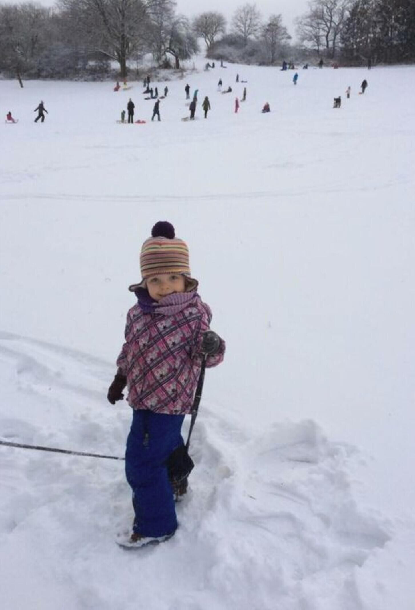 A child in a snowy outdoor area with a sled.