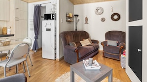 Ein gemütliches Wohnzimmer mit einer Couch, zwei Sesseln, einem Couchtisch und einem Essbereich mit Tisch und Stühlen.