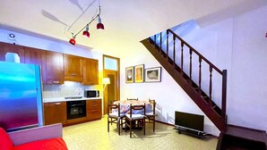 A compact living space with a kitchen, dining area, and a staircase. - Apartment in Caorle Near Beach & Pool (Caorle)