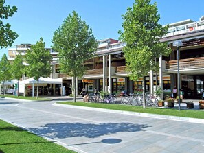 A pedestrian area with a row of shops, including a pharmacy and a market. - Apartment in Caorle Near Beach & Pool (Caorle)