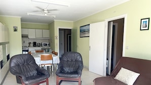A living room with two leather chairs, a brown sofa, and a coffee table with remote controls. - Apartment in Nieuwpoort With sea Views (Nieuwpoort)