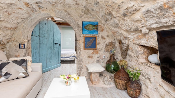A rustic stone interior with a blue door, a white table with flowers, and a fireplace. - Stylishly Decorated Apartment With Private Terrace (Punat)