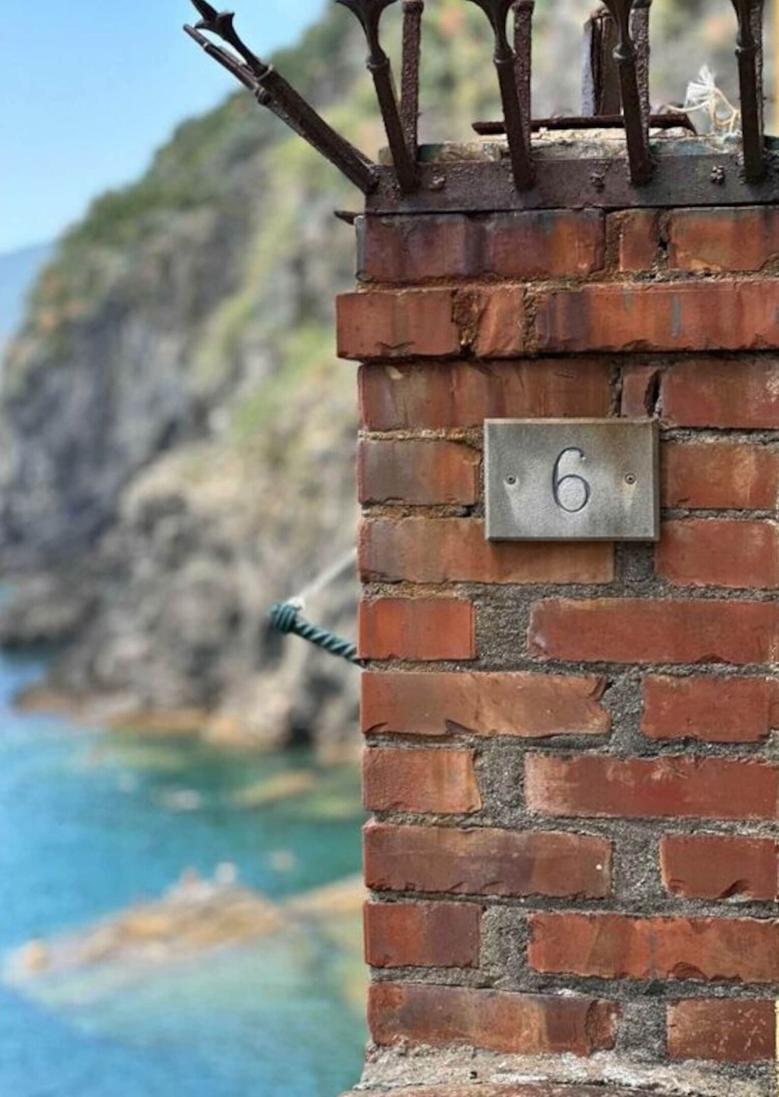 A brick wall with a metal plaque displaying the number 6.