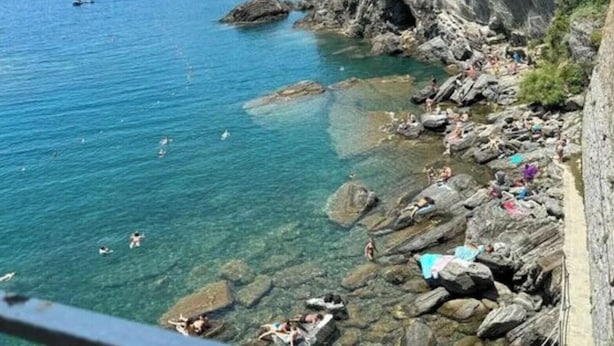 A rocky coastline with clear blue water, a few boats, and people enjoying the beach. - La Casa sul Mare (Vernazza)