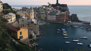A coastal town with colorful buildings, a historic church, and a harbor with boats. - La Casa sul Mare (Vernazza)