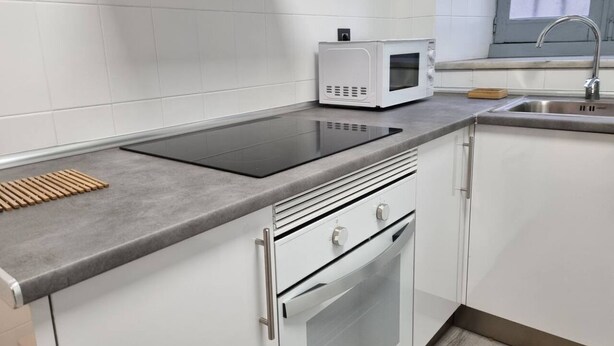 A kitchen with a built-in stove, microwave, and stainless steel sink.