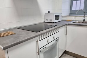Une cuisine équipée d’une cuisinière intégrée, d’un four à micro-ondes et d’un évier en acier inoxydable.