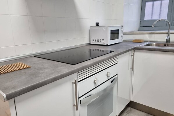 A kitchen with a built-in stove, microwave, and stainless steel sink.