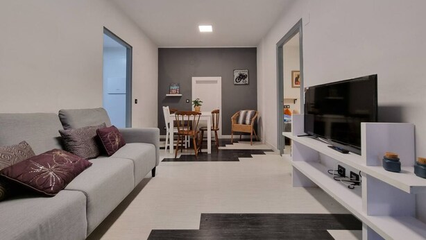 Una sala de estar moderna con sofá, televisor y comedor.