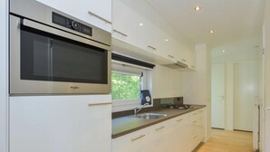 A modern kitchen with a built-in microwave, stainless steel appliances, and a window above the sink. - Lovely Apartment in Wolpinghausen (Zorgvlied)