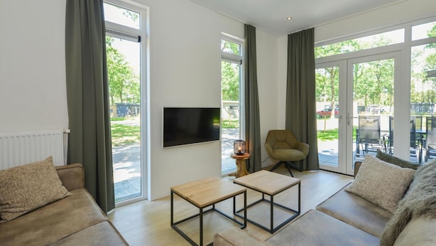 A modern living room with a sofa, a coffee table, and a TV mounted on the wall. - Lovely Apartment in Wolpinghausen (Zorgvlied)