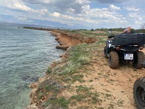 A quad bike parked on a dirt path by a cliffside overlooking a body of water. - Blizina Mora II Modern Retreat (Vir)