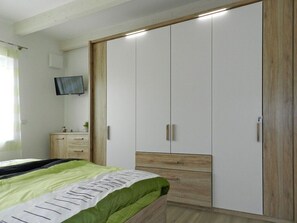 A bedroom with a bed, a wardrobe, a television, and a small cabinet. - Holiday Apartment Deck Boat (Butjadingen)